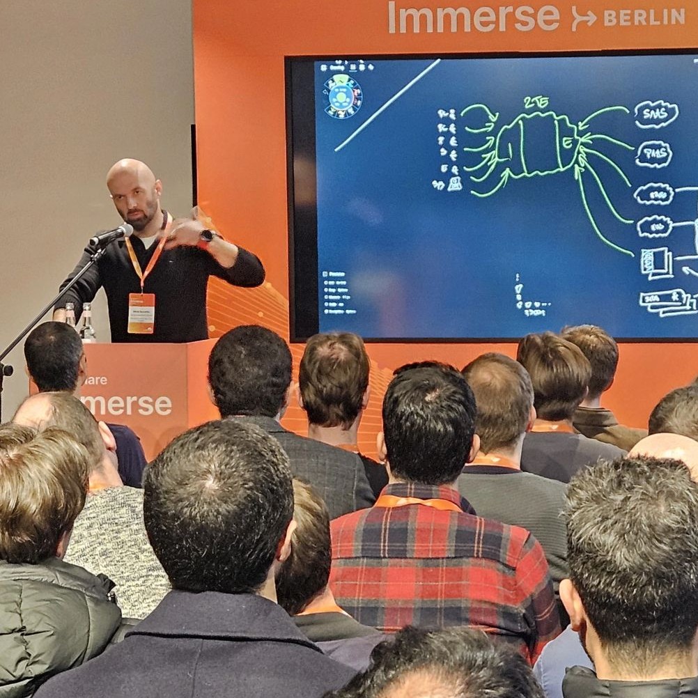 A speaker beside a network diagram at Cloudflare Immerse Berlin