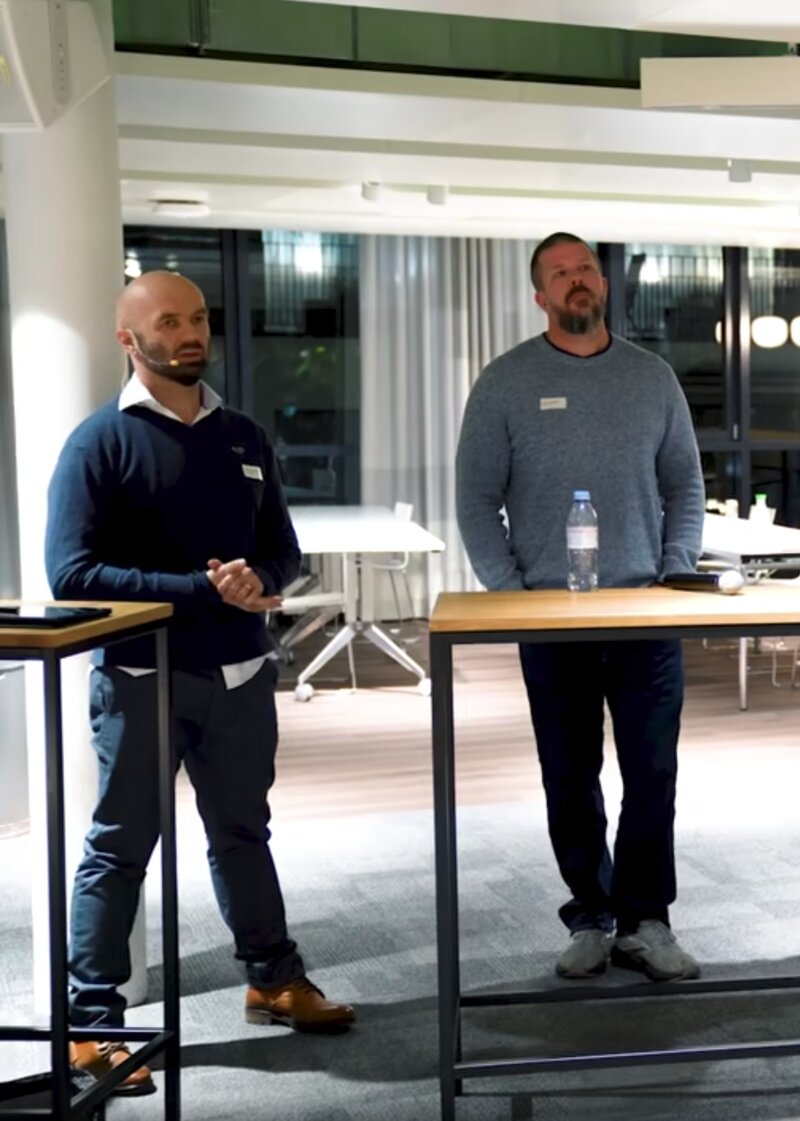 Two speakers beside standing tables in an office