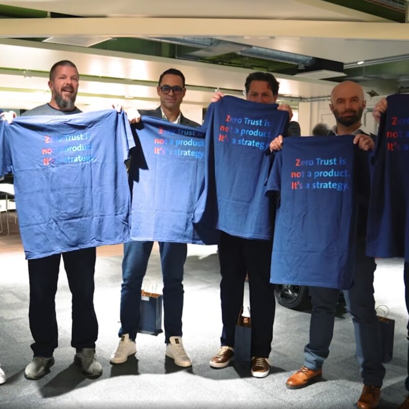 Four people holding T-shirts with the words “Zero Trust is not a product. It's a strategy.”