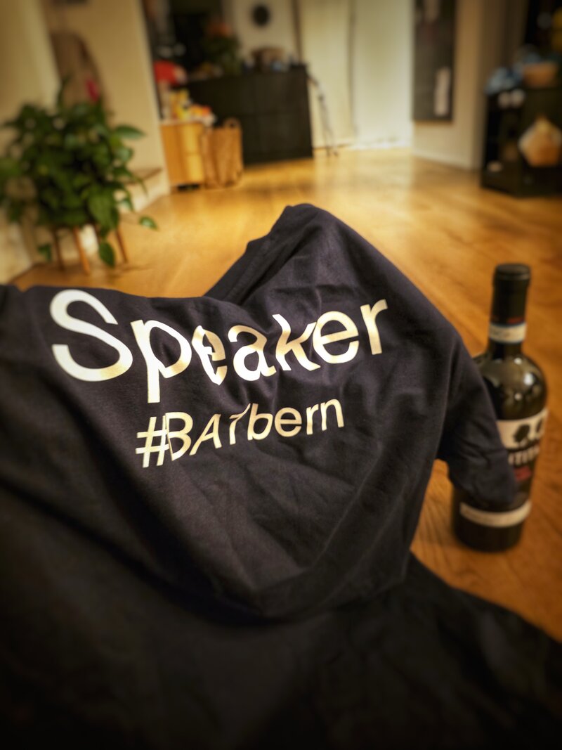 A dark T-shirt marked “Speaker” beside a bottle